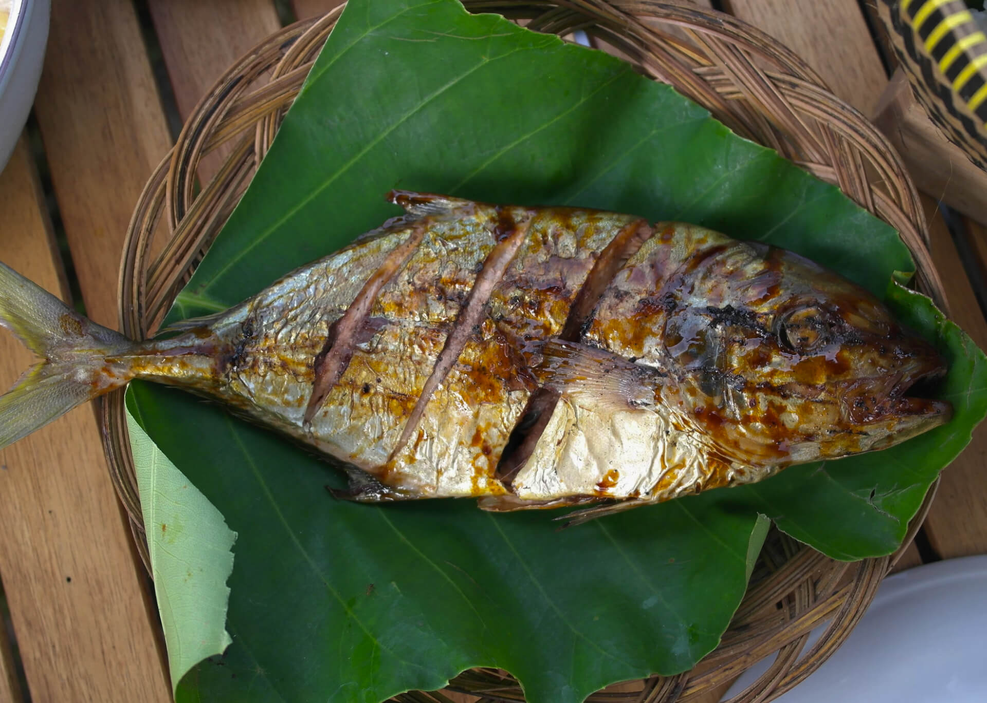 Grilled fish on banana leaf in woven bamboo basket